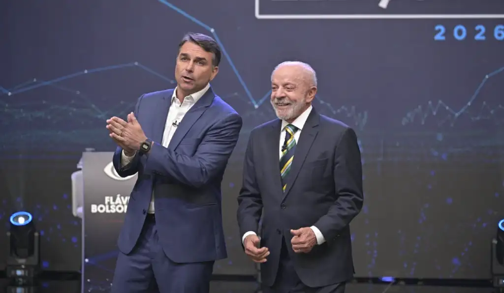 Flávio reduz provocações, mas insiste no jogo sujo de aparecer atrás de Lula nos debates